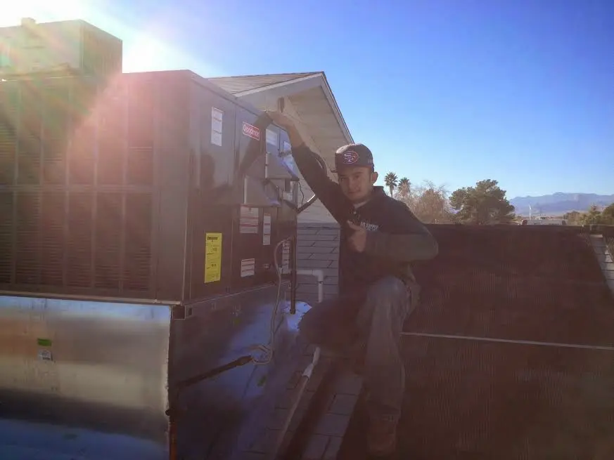 HVAC technician performing AC Tune-Up on a rooftop unit in Amherst