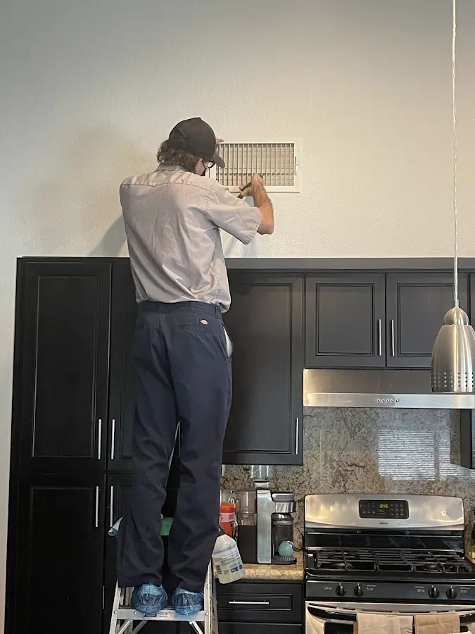 Technician inspecting an air vent during HVAC service in Amherst